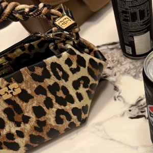 Leopardmönstrad ganni väska - Unik ganni väska i leopard mönster! Knappt använd. Köptes på NK Göteborg våren 2024. Kvitto, dustbag samt etikett finns och mer bilder kan fås vid intresse. 