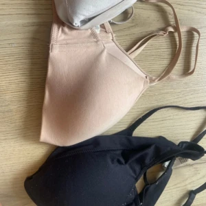3-pack basic bandeau toppar - Tre bh-ar  i svart, beige och vit. Alla ärmlösa med smala axelband och lätt vadderade kupor för snygg passform. Perfekta att bära under skjortor eller som de är. Mjukt och stretchigt material för extra komfort.