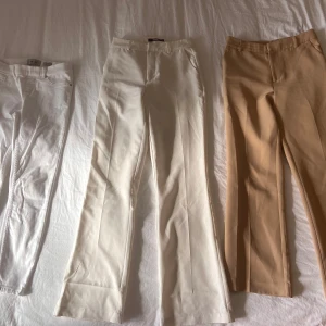 Mix av byxor i olika färger och stilar - Säljer ett gäng byxor: vita jeans, ljusbeige och beige kostymbyxor, svarta leggings från Adidas med vita ränder, svarta bootcutbyxor och ett par rosa mjukisbyxor med snörning. Perfekt för dig som vill ha variation i garderoben!