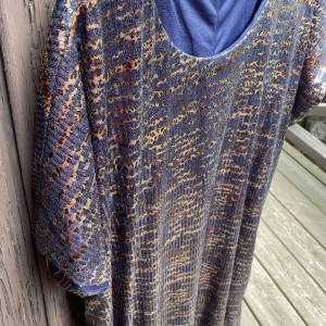 Zizzi paljettklänning i skimrande mönster stl S - Säljer en blå glittrig klänning från Zizzi med korta ärmar. Klänningen har ett skimrande mönster i blått och guld och är tillverkad i ett stretchigt material. Perfekt för dig som vill sticka ut lite extra!