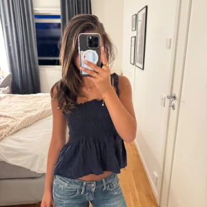Mörkblå smockad linnetopp från SHEIN - Supersöt mörkblå linnetopp från SHEIN med smockad överdel och volang nertill. Toppen har tunna axelband som knyts upptill och en lätt rynkad kant vid bysten. Perfekt för varma dagar och enkel att styla med jeans eller kjol.💖