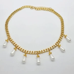 Guldhalsband med droppformade pärlor - Snyggt halsband i guldton med chunky kedja och sju droppformade vita pärlor som hänger längs hela kedjan. Perfekt statement piece med lyxig vibe och cool design. Lås med justerbar kedja för bästa passform. Perfekt för dig som vill sticka ut med din stil.