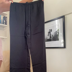 Svarta Satinbyxor med snörning - Säljer mina Svarta Satinbyxor - XS från Gina.  Helt nya med prislapp på, endast testade. Säljer pga för små för mig! Helt slutsålda på hemsidan! Supersköna och fint material.