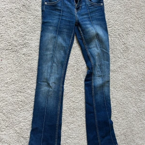 Blå bootcut jeans från Bershka - Snygga blå jeans från Bershka i bootcut-modell med klassisk femficksdesign och dubbla silverfärgade knappar fram. Pris kan diskuteras!
