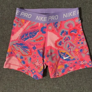 Nike PRO shorts - Jättegulliga rosa Nike PRO shorts med färgat mönster. Shortsen har en elastisk midja och skön passform. 💗Använda 2 ggr, väldigt bra skick!! M barnstorlek vilket motsvarar XS 💕