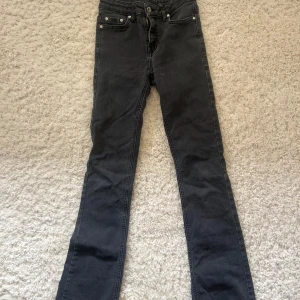 Svarta vanliga boot cut jeans  - Snygga svarta jeans med klassisk femficksdesign och smal passform. Jeansen har dragkedja och knapp framtill, samt raka bakfickor. Perfekta för dig som gillar en stilren look. Märket är grunt men är köpta för 699 på kidsbrandstore. Storlek är 158 cm