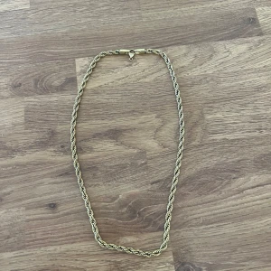 Guldigt tvinnat halsband - Snyggt halsband i guldton med tvinnad kedja som ger en cool och stilren look. Perfekt för att lyfta din outfit med lite extra bling. Låset är diskret och smidigt, och kedjan har en klassisk design som passar till många stilar.