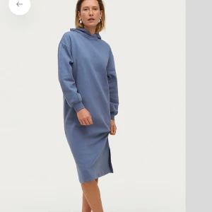 Blå klänning med huva - Mysig blå långklänning med huva och långa ärmar. Klänningen har en rak passform och slits i sidan. Köpt för 399 och endast testad .