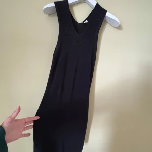 ARKET Svart stickad ärmlös klänning M - Supersnygg svart stickad klänning i storlek M. Modellen är ärmlös med breda axelband och v-ringad hals. Materialet är grovstickat och ger en cool struktur. 
