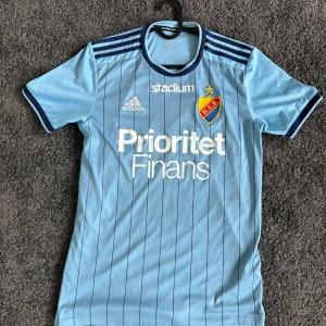 Djurgården fotbollströja och shorts Adidas - Säljer Djurgårdens IF matchtröja i ljusblått med tunna mörkblå ränder, 19 på ryggen. Även ett par blåa adidas shorts, 8,5/10 i skick. Tröjan säljs för 650kr och shortsen för 150kr allt tillsammans blir 700kr. Tröjan är i storlek S och shortsen är i storlek M