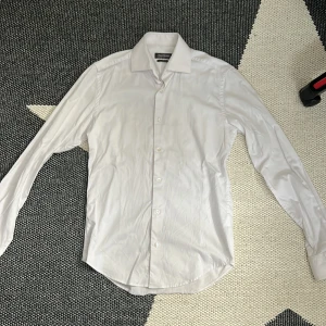 Vit slim fit skjorta Dressmann XS - Vit skjorta från Dressmann i slim fit-modell, tillverkad i stretchig bomull. Klassisk krage, långa ärmar med manschett och knappar framtill. Snygg och stilren design som passar dig som gillar en clean look. Lite ostruken på bild 