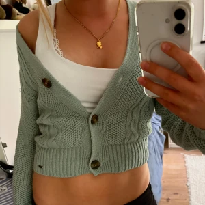 Turkosgrön kofta med knappar - Säljer nu en såå fin croppad kofta i turkos/mintgrönt med grovstickat mönster och snygga stora knappar framtill. Tröjan har lång ärm, ribbade muddar och kabelstickade detaljer. Den jättenajs o ba kasta över vad som helst och är i bra skick☺️💖