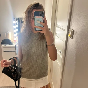 Stickad ärmlös hoodie i ljus grön - Säljer en stickad väst i ljusgrön med huva och ribbad struktur. Tröjan är ärmlös och har en loose passform, perfekt att styla med kjol eller jeans. Enkel och clean look som funkar året runt. 