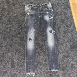 Grå/blå slitna jeans - Snygga grå jeans med slitningar och fransar vid bensluten. De har en skinny passform och är dekorerade med slitna detaljer både fram och bak. Perfekta för en trendig look.