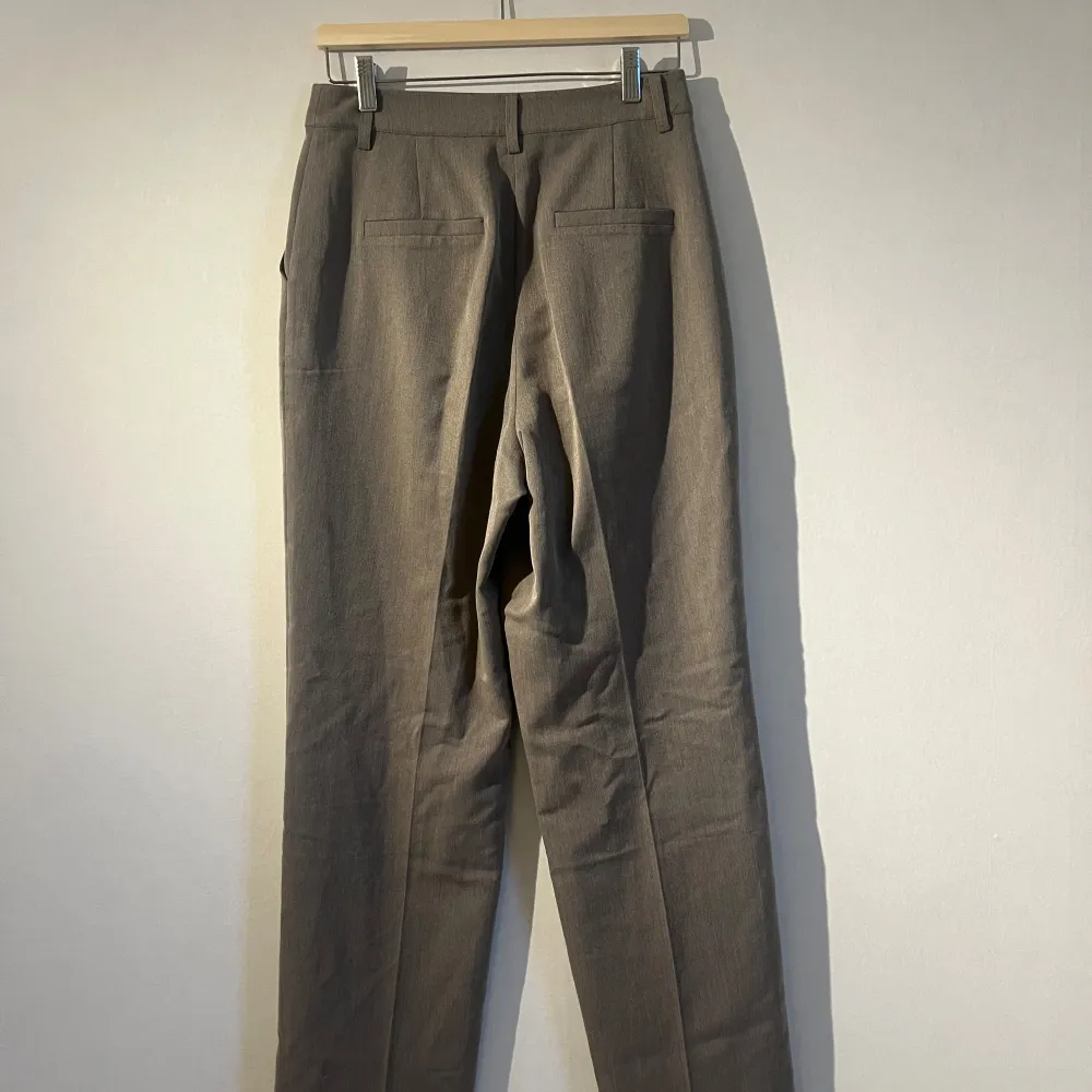 Snygga beige kostymbyxor från NA-KD i storlek 38. Byxorna har en klassisk design med raka ben och hög midja. Perfekta för en stilren look.. Farkut & Housut.