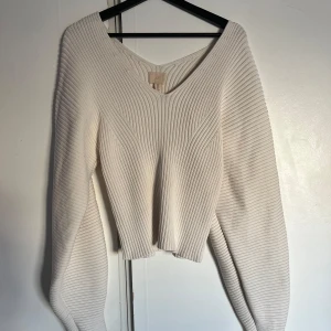 Vit ribbad tröja från H&M - Säljer en stilren vit ribbad tröja från H&M. Tröjan har en v-ringad design och långa ärmar, perfekt för en chic och bekväm look. 