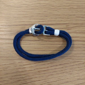 Blått armband med silverdetaljer - Snyggt blått armband med en stilren design och silverfärgad låsdetalj. Armbandet har en vit accent som ger en fräsch touch. Perfekt för att komplettera din stil med en marin känsla.