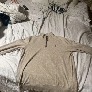 Ralph Lauren halfzip  - Säljer en stilren beige tröja från Polo Ralph Lauren. Tröjan har en dragkedja vid halsen och är i slim fit. Perfekt för en avslappnad men ändå elegant look. Golf tröja men väldigt snygg till varadagen Också storlek M kostar 2800 ny