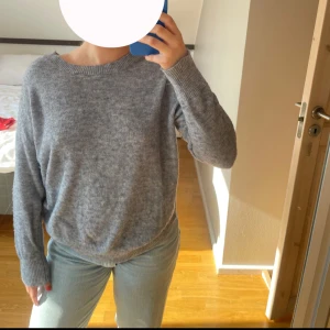 Grå/blå stickad tröja - Säljer en mysig grå stickad tröja med rund halsringning. Tröjan har långa ärmar och ribbade muddar vid ärmslut och nederkant. Perfekt för kyligare dagar!