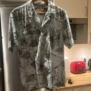Blommig  skjorta från Levi's - Jag säljer nu min skjorta för att den är för liten och den passar 180+ Säljer en stilren kortärmad skjorta från Levi's i ljusblått med svart blommönster. Perfekt för en somrig look!