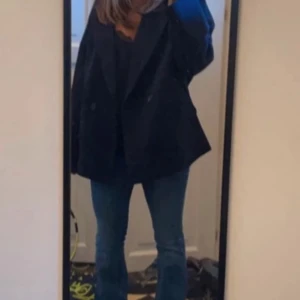 Mörkblå kappa - Snygg mörkblå kappa med dubbelknäppning och en avslappnad passform. Perfekt för kyligare dagar med sin stilrena design och långa ärmar. En klassisk look som funkar till det mesta.