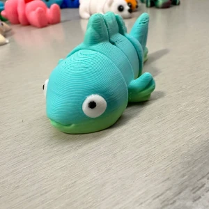 Turkos och grön leksaksfisk - Charmig leksaksfisk i turkos och grön färg med stora vita ögon. Den är segmenterad vilket gör att den kan röra sig flexibelt. Perfekt som en rolig dekoration eller leksak.