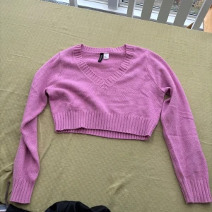 Rosa croppad tröja med v-ringning - Säljer en söt rosa croppad tröja med v-ringning. Tröjan har långa ärmar och ribbade kanter som ger en snygg passform. Perfekt för en avslappnad stil. Aldrig använd så nytt skick 🌸🌸