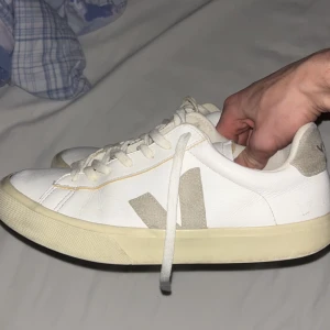 Vita sneakers från Veja - Snygga vita sneakers från Veja med beige detaljer och snörning. Skorna har en klassisk design med en bekväm passform och är perfekta för en stilren look.