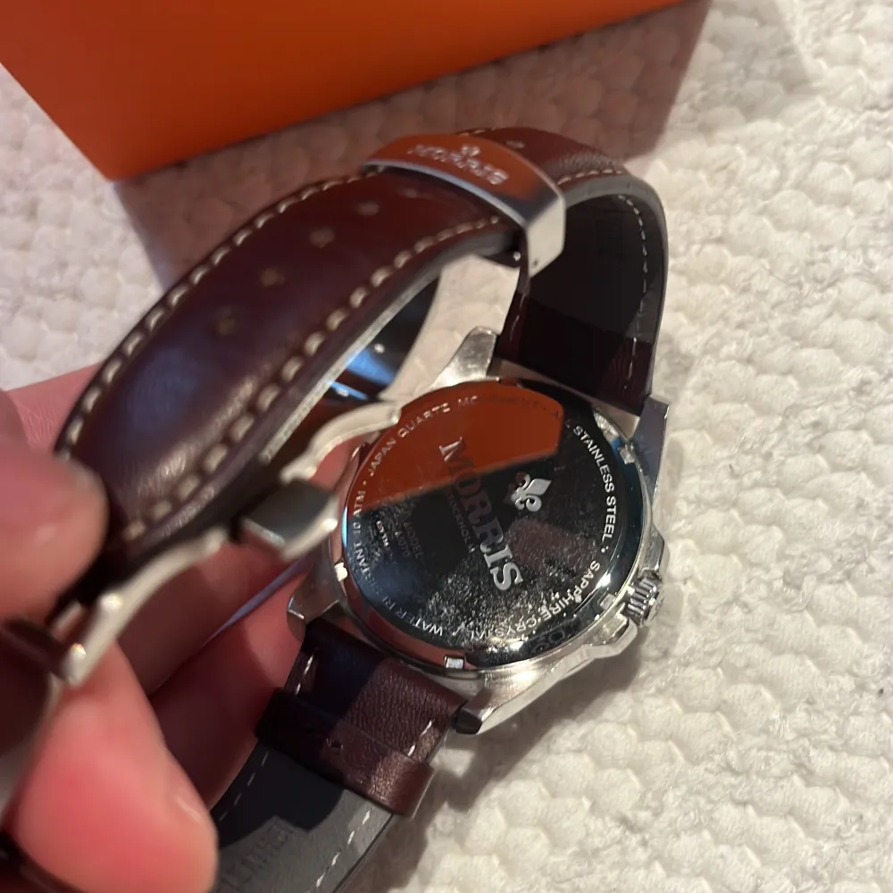 Snygg klocka från Morris med en stilren vit urtavla och datumvisning. Klockan har ett brunt läderarmband och boett i rostfritt stål. Perfekt för den som söker en klassisk och tidlös stil. Levereras i originalförpackning.. Asusteet.