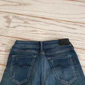 Blå jeans från Replay - Snygga blå jeans från Replay med en tight passform. De har en klassisk femficksdesign och en dragkedja framtill. Perfekta för en stilren look.