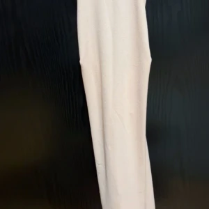 Ljusrosa klänning - Elegant ljusrosa klänning med axelbandslös design. Perfekt för sommarens festligheter. Klänningen har en smickrande passform och är tillverkad i ett mjukt material.