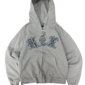 Grå hoodie med tryck från K1X - Säljer en tvärfet vintage hiphop/rap hoodie från K1X, Extremt hög kvalité och asskön att ha på sig.  Defekter är endast ärmarna på bild och en av sömen på fickorna har lossat lite. Bredd: 60cm Längd: 69cm