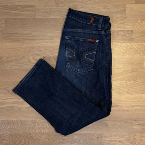 Mörkblå jeans  - Snygga mörkblå jeans med klassisk femficksdesign och coola detaljer på bakfickorna. De har en normal passform och är perfekta för en avslappnad stil. Jeansen har en knappgylf och är tillverkade i slitstarkt denim.