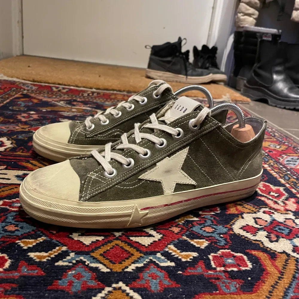 Snygga olivgröna sneakers från Golden Goose med en vit stjärna på sidan. Skorna har en klassisk snörning och en vit sula med en lätt sliten look för en vintagekänsla. Perfekta för en avslappnad stil.. Kengät.
