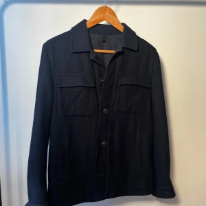 Mörkblå overshirt från Massimo Dutti - Säljer den här fina overshirt en från Massimo dutti. Jackan har en defekt som är att en av knapparna på ärmen inte längre finns, de gör alltså att man inte kan stänga mudden på en av armarna! Annars är jackan i perfekt skick och perfekt till våren! 