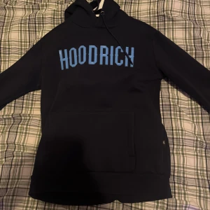 Svart hoodie från Hoodrich - Säljer en svart hoodie från Hoodrich med ett par byxor också från hoodrich. Den har en stor ficka framtill och justerbar huva med dragsko. Perfekt för en avslappnad stil.