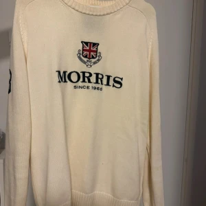 Vit tröja från Morris - Säljer en stilren vit tröja från Morris med broderad logotyp och text 'Morris Since 1968' på framsidan. Tröjan är tillverkad i 100% bomull och har långa ärmar. Perfekt för en klassisk och tidlös look. Storlek L. Inköpspris: 1299 kr.