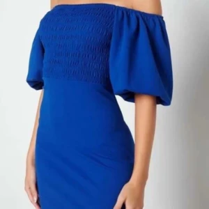 Blå offshoulder klänning - Snygg blå offshoulder klänning med puffiga ärmar och smockdetaljer på överdelen. Perfekt för en somrig look eller en kväll ute. Klänningen har en figurnära passform som framhäver silhuetten.