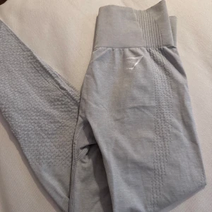 Grå leggings från Gymshark - Snygga grå leggings från Gymshark med ribbad midja och diskret logga. Perfekta för träning med sin stretchiga passform och bekväma material. 