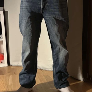 Blå jeansbyxor - Säljer ett par klassiska blå jeansbyxor med en straight passform. De har en traditionell femficksdesign och knappar i gylfen. Perfekta för en avslappnad stil.