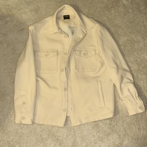 Beige overshirt från Zara - Snygg beige overshirt från Zara med knappar framtill och två bröstfickor. Perfekt för lager-på-lager-stil. Långärmad design med klassisk krage. Slutsåld.