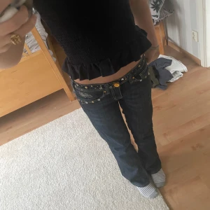 Mörkblå jeans med nitar - Snygga mörkblå jeans med låg midja och dekorativa nitar. Byxorna har en bootcut/straight-stil och är perfekta för en trendig look. De har också detaljerade fickor med nitar och broderi.. Innerben:72cm, ytterben:94cm, Benöppning:19cm, Storlek:27! Pris kan diskuteras! Köpte dem i tyskland så märket är ranis ladies!