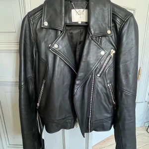 Svart skinnjacka från Dante 6 - Snygg svart skinnjacka från Dante 6 med asymmetrisk dragkedja och flera dragkedjefickor. Jackan har en klassisk bikerstil med långa ärmar och tryckknappar vid kragen. Perfekt för en cool look! Använd 2 gånger och nypris är lite över 4000kr✨