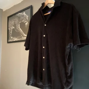 Svart kortärmad skjorta från Jack & Jones - Snygg svart kortärmad skjorta från Jack & Jones med knappar. Skjortan har en klassisk krage och är tillverkad i ett mjukt material. Använd fåtal gånger och är storlek S men passar M. Hör av dig vid fler bilder el frågor!