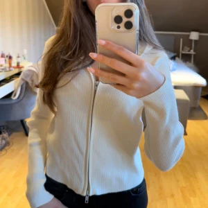 Vit ribbad tunn hoodie med dragkedja - Säljer en jätte fin vit ribbad hoodie med dragkedja. Aldrig använd i toppen skick. Hittar inte storleken men passar mig som bär xs. Skriv vid frågor ❤️