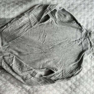 Grå ribbad polotröja - Säljer en stilren grå ribbad polotröja med långa ärmar. Perfekt för kyligare dagar och enkel att matcha med olika outfits. Tröjan har en klassisk design med en bekväm passform. Tröjan är lite skrynklig på bilden🤭