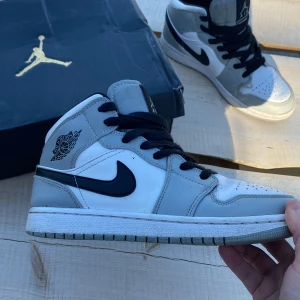 Nike Air Jordan 1 mid grå och vit  - Säljer ett par Jordan one mid i storlek 38,5. Skorna är i bra skick och låda medföljer. 