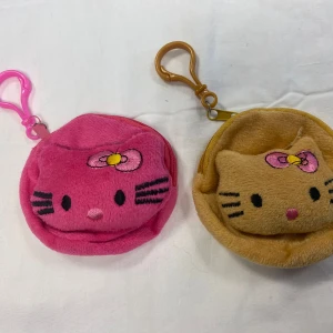2st Söta Hello Kitty Myntpåse  - Två små plånböcker  i rosa och beige. Båda har en praktisk karbinhake för enkel fastsättning. Perfekta för att förvara småsaker eller mynt. Helt ny 