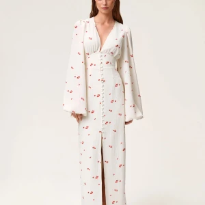 Vit långklänning med blommönster - Superfin vit långklänning med små röda blommor och v-ringning från adoore. Endast använd en gång så i fint skick! Pris kan diskuteras, skriv för fler bilder💞💞.