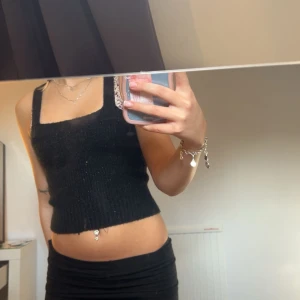 stickad glitter linne - Snygg svart ribbad linnetopp med en croppad passform. Perfekt för en stilren look. Toppen har breda axelband och en fyrkantig halsringning.